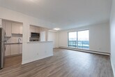 Located at 836 Talwood Dr in Peterborough, Ontario, this one-bedroom, one-bathroom unit offers a thoughtfully designed layout with a clean, modern aesthetic throughout. Light-toned hardwood flooring flows seamlessly across the entire unit, complementing the crisp white walls and bright, airy atmosphere.

The open-concept living, dining, and kitchen area forms the heart of the unit. The living room is generously proportioned and features a large sliding glass door that opens onto a private balcony, offering pleasant outdoor views and filling the space with natural light. Baseboard heating runs beneath the windows, ensuring year-round comfort.

The kitchen is well-appointed with white shaker-style cabinetry, subway tile backsplash, stainless steel appliances including a refrigerator and dishwasher, and a functional countertop layout. A pass-through opening connects the kitchen to the living and dining area, enhancing the open feel of the space.

The bedroom is a comfortable, well-sized room with its own sliding door access to a balcony, a window with outdoor views, and ample wall space for furniture arrangement.

The bathroom features tile flooring, a full soaker tub with a subway tile surround, and a clean, minimal design. Overall, this unit presents a fresh, move-in-ready space with modern finishes throughout.