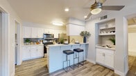 Located on W Main St in Mesa, Arizona, this single-floor, 2-bedroom, 2-bathroom residence offers a thoughtfully designed layout with modern finishes throughout. The open-concept kitchen and living area serves as the heart of the home, featuring white shaker cabinetry, a grey subway tile backsplash, light quartz countertops, and a full suite of stainless steel appliances. A peninsula breakfast bar with seating provides a casual dining option, while a dedicated wet bar area with built-in shelving adds extra functionality. Wood-look flooring flows throughout the main living areas, complemented by a ceiling fan overhead. The living room is bright and inviting, anchored by a sliding glass door that opens to an outdoor view and fills the space with natural light. The spacious primary bedroom features plush carpeting, a sliding closet, and a private en-suite bathroom with a shower-tub combo. The second bedroom is equally comfortable, also with carpet and a closet. Both bathrooms are clean and functional, with wood-look tile flooring. A dedicated laundry room houses a full-size washer and dryer. A connecting hallway ties all rooms together efficiently, making excellent use of the available footprint.