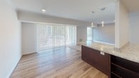Located at 8132 Prescott Drive, Suite 101 in Vienna, Virginia, this single-floor unit offers a thoughtfully designed layout that balances modern finishes with comfortable living spaces. The kitchen is a standout feature, showcasing rich dark-espresso cabinetry, light granite countertops, a soft aqua glass tile backsplash, and a full suite of stainless steel appliances including a gas range, over-the-range microwave, and dishwasher. Wood-look flooring runs throughout the kitchen, which also features a peninsula with pendant lighting overhead, providing both additional counter space and an open connection to the living area. The living and dining area is bright and open, with large windows and a sliding glass door dressed in vertical blinds that invite generous natural light while offering outdoor views. Plush neutral carpeting extends through the living space and into the bedrooms, lending a warm, comfortable feel. The bedrooms are well-proportioned, with large windows, ceiling fans, and access to closets. The bathroom is clean and functional, featuring a tiled tub-and-shower combination, a dark wood vanity, tile flooring, and brushed nickel fixtures throughout. This suite presents a polished, move-in-ready space in a desirable Vienna location.