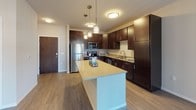 Located on Nobel Drive in Fitchburg, Wisconsin, this single-floor residence offers a thoughtfully designed layout with modern finishes and a cohesive, contemporary aesthetic throughout. The kitchen serves as a focal point of the home, showcasing rich dark-espresso cabinetry, light countertops, and a full suite of stainless steel appliances including a refrigerator, range, microwave, and dishwasher. A central island provides additional prep space and casual seating, while stylish pendant lighting above adds a polished touch. The kitchen flows naturally into the living area, which features durable wood-style flooring and access to a sliding glass door, allowing for natural light to fill the space. The living room is generously proportioned and includes a ceiling fan, creating a comfortable and functional gathering area. Bedrooms are finished with plush carpeting, ceiling fans, and windows that bring in natural light and views of the surrounding neighborhood. The bathroom is well-equipped with a combined tub and shower, dark vanity cabinetry with brushed nickel hardware, and tile flooring. Throughout the residence, neutral wall tones, clean lines, and consistent materials create a calm and inviting atmosphere well-suited for everyday living.