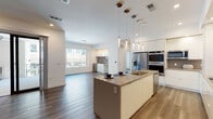 This contemporary single-floor residence at 5211 Peachtree Blvd in Chamblee, Georgia, offers a thoughtfully designed open-concept layout with high-end finishes throughout. The centerpiece of the home is a sleek, modern kitchen featuring a large island with a quartz countertop, undermount sink, and elegant pendant lighting. Stainless steel appliances—including a French door refrigerator, double wall ovens, and a built-in microwave—complement the floor-to-ceiling white cabinetry and a professional-grade range hood. Rich hardwood flooring flows seamlessly from the kitchen into the open living area, which is bathed in natural light from large windows. The primary bedroom is generously proportioned, featuring a ceiling fan, dual sliding closets, and a well-organized walk-in closet with custom built-in shelving. The en-suite bathroom is finished with large-format tile flooring and a frameless glass walk-in shower. A secondary bedroom offers built-in closet storage and direct access to an additional bathroom. A dedicated laundry room provides a side-by-side washer and dryer, utility sink, and ample upper cabinetry. The private outdoor terrace is a standout feature, equipped with a ceiling fan, stainless steel wet bar, and beverage cooler—ideal for outdoor entertaining.
