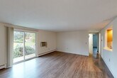 Located at 23 Cedar Pond Dr in Warwick, Rhode Island, this 2-bedroom, 1-bathroom residence offers a practical and well-organized single-floor layout. Hardwood-style flooring runs throughout, lending a cohesive and clean aesthetic to every room. The spacious living room is a standout feature, highlighted by a sliding glass door that opens to a private balcony and provides views of the surrounding greenery, allowing natural light to fill the space. A wall-mounted A/C unit and baseboard heating ensure year-round comfort. The living area flows into a dedicated dining room, creating a natural separation between spaces. The kitchen is accessed through an open doorway and features warm wood cabinetry, recessed lighting, ample counter space, and full-size appliances including a range and refrigerator. The generously sized primary bedroom is brightened by two windows overlooking the outdoors, while the second bedroom also benefits from natural light and baseboard heating. Four closets are distributed throughout the unit, offering substantial storage. The bathroom includes a full tub and shower combination with white tile surround and an accessibility grab bar. Textured ceilings add a subtle architectural detail throughout the home.