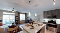 This single-story, one-bedroom, one-bathroom residence offers a thoughtfully designed open-concept layout that seamlessly connects the kitchen, dining, and living areas. The kitchen is a standout feature, showcasing dark wood-grain cabinetry, granite countertops, a large center island with a stainless steel undermount sink, subway tile backsplash, and a full suite of stainless steel appliances including a refrigerator, range, microwave, and dishwasher. Pendant lighting and under-cabinet illumination enhance the kitchen's modern aesthetic.

The living area is generously proportioned, featuring wood-style flooring, a ceiling fan, and a sliding glass door that opens to a private balcony, allowing abundant natural light throughout. The bedroom is carpeted and comfortably sized, with a large window offering outdoor views and a ceiling fan for added comfort. It connects to a walk-in closet equipped with wire shelving and hanging rods. The full bathroom includes a soaking tub with a tiled surround, granite vanity countertop, and tile flooring. Throughout, neutral tones and clean finishes create a cohesive, contemporary ambiance.