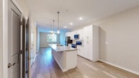 Located at 2860–2878 N Federal Blvd in Denver, CO, this well-appointed one-bedroom, one-bathroom unit offers a thoughtfully designed single-level layout with modern finishes throughout. The open-concept kitchen and living area serves as the heart of the home, anchored by a generous kitchen island with a granite countertop and integrated sink, illuminated by stylish pendant lighting. White shaker-style cabinetry extends to the ceiling, providing ample storage, while stainless steel appliances — including a refrigerator, range, and microwave — complete the kitchen. Light hardwood flooring flows seamlessly throughout the entire unit, lending a cohesive and airy feel. The living area is open and bright, with natural light filtering in from a window that views onto surrounding greenery. The bedroom is a comfortable, well-proportioned retreat featuring a large window with blinds, light-toned walls, and direct access to both a walk-in closet equipped with wire shelving and a full bathroom. The bathroom mirrors the home's refined aesthetic with a white vanity, granite countertop, large mirror, and a shower-tub combination. A hallway connects the private spaces efficiently, making the overall layout feel functional and well-organized.