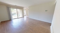 Located at 10337 Society Park Drive in Cockeysville, Maryland, this single-floor residence offers a well-designed layout with a clean, neutral aesthetic throughout. The main living area is generously sized, featuring smooth hardwood-style flooring that reflects natural light pouring in through large sliding glass doors. These doors open to an outdoor view of mature greenery, bringing a sense of the outdoors inside. A ceiling fan adds functional comfort to the living space, which flows naturally into adjacent areas of the home. The kitchen is a standout feature, showcasing dark espresso-toned cabinetry paired with granite-look countertops and a mosaic tile backsplash that adds visual texture. Stainless steel appliances, including a dishwasher and range, complete the modern, functional kitchen. The bedrooms are carpeted in neutral tones, providing a soft and comfortable atmosphere. One bedroom benefits from a window with an outdoor view, adding natural light to the space. Throughout the residence, walls are finished in a soft cream tone, creating a bright and cohesive backdrop. The overall layout, as seen from the dollhouse view, is open and efficiently organized, making excellent use of the single-floor footprint.