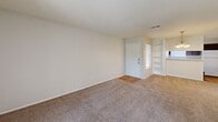 Located at 803 Flame Cir in San Antonio, Texas, this single-story, two-bedroom, one-bathroom home offers a practical and comfortable layout. The living area is carpeted and bathed in natural light, featuring a built-in bookshelf and access to a sliding glass door that opens to the outdoors. Textured ceilings are present throughout much of the home, adding a classic residential character.

The galley-style kitchen is efficiently designed with dark cabinetry, light countertops, a double-basin stainless steel sink, a range, and a dishwasher. Wood-look flooring runs through the kitchen, providing a clean contrast to the carpeted living spaces.

The primary bedroom is generously sized, featuring a ceiling fan, a window with outdoor views, and direct access to a walk-in closet. A second bedroom also offers carpeted flooring, a ceiling fan, and a bright window. Notably, the home includes four closets in total, providing exceptional storage throughout.

The bathroom features a long vanity with dark cabinetry, a wide mirror, and stylish light fixtures overhead, with wood-look flooring completing the space. The home's neutral color palette, plentiful natural light, and well-distributed layout make it a highly functional and inviting residence.