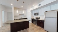 This single-floor residence offers a thoughtfully designed layout with a clean, contemporary aesthetic throughout. The kitchen serves as a standout centerpiece, showcasing a striking two-tone design with white shaker-style upper cabinets and rich dark lower cabinetry, all complemented by a classic white subway tile backsplash and light quartz countertops. A central island with pendant lighting provides additional workspace and casual seating, while stainless steel appliances — including a range, microwave, dishwasher, and refrigerator — complete the functional setup. Light wood-look flooring flows throughout the main living and kitchen areas, lending warmth and continuity to the space. The living area is bright and open, with natural light entering through a glass-paneled door. Bedrooms feature plush neutral carpeting, ceiling fans, and windows fitted with blinds that allow for ample light control. The primary bathroom is generously sized, offering a dark-cabineted vanity with a white countertop, a tub-shower combination, and direct access to a spacious walk-in closet with built-in shelving. A secondary bathroom provides a clean, functional tub-shower combo with light wood-look flooring. The overall ambiance is modern, clean, and move-in ready.