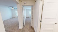 Located at 207 E Mountcastle Dr in Johnson City, Tennessee, this single-floor unit offers a clean, functional layout designed for comfortable everyday living. The kitchen is a standout feature, outfitted with rich dark cabinetry, a textured tile backsplash, light countertops, and a full suite of stainless steel appliances including a refrigerator, range, microwave, and dishwasher. Recessed lighting illuminates the kitchen area, which opens directly into the main living space finished with wall-to-wall carpeting throughout.

The living areas are bright and neutral, with crisp white walls and generous natural light streaming through large windows fitted with blinds. Each room is equipped with a wall-mounted HVAC unit for individual climate control, and several rooms feature ceiling fans for added comfort. The outdoor views visible through the windows offer a pleasant, tree-lined backdrop.

Storage is well-considered, with closet space featuring wire shelving for organization. The bathroom is neatly appointed with a tub-shower combination adorned with white tile surround, a dark wood vanity, light countertop, and wood-look flooring that adds warmth to the space. The overall aesthetic is clean, move-in ready, and functional throughout.