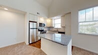 Located at 100 Shellbark Way in Savannah, Georgia, this two-story home offers a thoughtfully designed layout across two levels. The kitchen is a standout feature, showcasing white beadboard cabinetry, granite countertops, a subway tile backsplash, stainless steel appliances, and a central island — all complemented by warm hardwood-style flooring and natural light from a window above the sink. Soaring vaulted ceilings in the main living area create an open, airy atmosphere, while carpeted flooring adds warmth throughout. A carpeted staircase with a classic wood handrail connects the two floors. The upper level features additional rooms with angled, vaulted ceilings that lend a charming architectural character, along with built-in access panels for convenient storage. The bedrooms are bright and comfortable, with large windows offering views of the surrounding greenery and ceiling fans for added comfort. The bathrooms are well-appointed with white cabinetry, dark granite countertops, soaking tubs with tile surrounds, and hardwood-style flooring. Overall, this home combines functional design with inviting details throughout.