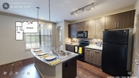 Located at 500 S Lasalle St in Durham, NC, this one-bedroom, one-bathroom residence offers a thoughtfully designed single-floor layout with a comfortable and functional living environment. The kitchen serves as a standout feature, showcasing dark wood cabinetry, granite countertops, a tile backsplash, and a generously sized island with a double stainless steel sink and pendant lighting overhead. Black appliances, including a refrigerator, range, and built-in microwave, complete the well-equipped cooking space. Rich hardwood flooring extends through the main living areas, complemented by crown molding and elegant arched doorways that lend architectural character throughout. The living area features a tray ceiling with crown molding detail and an arched window that allows natural light to fill the room. The spacious primary bedroom is finished with plush carpeting, a ceiling fan, and an arched window offering outdoor views. Two closets provide ample storage. The bathroom includes a tiled tub-shower combination set within an arched alcove, paired with granite countertops and tile flooring. Track lighting and recessed fixtures ensure well-lit spaces throughout this refined Durham residence.