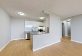Located at 10127 121 Street NW in Edmonton's desirable Glenora neighbourhood, this one-bedroom, one-bathroom unit offers a well-organized and functional layout spread across a single floor. Light-toned hardwood flooring runs throughout the unit, creating a warm and cohesive feel from room to room.

The combined kitchen and living area forms the heart of the unit. The galley-style kitchen is well-appointed with sleek white cabinetry, grey stone countertops, a white tile backsplash, and stainless steel appliances including a range, dishwasher, and refrigerator. The adjacent living area is bright and open, benefiting from large sliding glass doors that lead directly to a private balcony, allowing ample natural light to fill the space and providing views to the outdoors.

The spacious primary bedroom features a large window with exterior views, a sliding-door closet offering generous storage, and the same warm hardwood flooring found throughout. A dedicated closet space is also available elsewhere in the unit for additional storage needs.

The bathroom is finished with clean white subway tile surrounding a full soaker tub and shower combination, complemented by tile flooring and a wall-mounted mirror. Textured ceilings are present throughout the unit, adding a classic character to the overall interior.