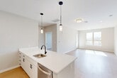 Located at 55 Seely School Dr in Groton, CT, this thoughtfully designed 2-bedroom, 2-bathroom residence offers a clean, contemporary aesthetic throughout its well-appointed single floor. The open-concept layout seamlessly connects the kitchen, dining, and living areas, creating a bright and airy communal space bathed in natural light from large windows. The kitchen is a standout feature, anchored by a generous island with a crisp white quartz countertop, white shaker cabinetry, a matte black faucet, and stainless steel appliances including a dishwasher and refrigerator. Stylish pendant lighting above the island adds a modern touch. Light-toned hardwood-style flooring flows throughout the main living areas, complementing the neutral color palette. The living room opens to a private balcony, extending the living space outdoors. Both bedrooms are carpeted for comfort, with the spacious primary bedroom featuring a walk-in closet equipped with wire shelving. The bathrooms are finished with marble-look tile flooring, wood-toned vanities, white countertops, and matte black fixtures. Additional conveniences include four closets, a dedicated laundry area, and a welcoming entrance, making this residence as functional as it is refined.