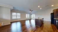 This two-floor home in Enfield, Connecticut offers a well-designed layout with thoughtful finishes throughout. The main living level showcases a generously sized open-concept space where the living area and kitchen flow seamlessly together. Rich, dark hardwood flooring extends throughout, complemented by recessed lighting and a ceiling fan overhead. Multiple windows allow abundant natural light to fill the space, with views of the surrounding neighborhood. A sliding glass door provides additional light and outdoor access.

The kitchen is outfitted with dark espresso cabinetry, granite countertops, and black appliances including a refrigerator, electric range, built-in microwave, and dishwasher. A center island with a sink adds both workspace and functionality.

The bedrooms feature the same hardwood flooring, crown molding, and ceiling fans, lending a cohesive and polished feel. The bathrooms include tile flooring and dark wood vanities; one bathroom offers a double-sink vanity with a large mirror, while another features a tub-shower combination with sliding glass doors.

The lower level includes an attached garage with a concrete floor, electrical panel, and interior access, completing this practical and well-appointed home.