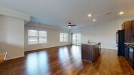 This two-floor home in Enfield, Connecticut offers a well-designed layout with thoughtful finishes throughout. The main living level showcases a generously sized open-concept space where the living area and kitchen flow seamlessly together. Rich, dark hardwood flooring extends throughout, complemented by recessed lighting and a ceiling fan overhead. Multiple windows allow abundant natural light to fill the space, with views of the surrounding neighborhood. A sliding glass door provides additional light and outdoor access.

The kitchen is outfitted with dark espresso cabinetry, granite countertops, and black appliances including a refrigerator, electric range, built-in microwave, and dishwasher. A center island with a sink adds both workspace and functionality.

The bedrooms feature the same hardwood flooring, crown molding, and ceiling fans, lending a cohesive and polished feel. The bathrooms include tile flooring and dark wood vanities; one bathroom offers a double-sink vanity with a large mirror, while another features a tub-shower combination with sliding glass doors.

The lower level includes an attached garage with a concrete floor, electrical panel, and interior access, completing this practical and well-appointed home.
