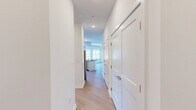 Located at 37 N York Road in Hatboro, PA, this well-appointed one-bedroom, two-bathroom unit delivers a clean, modern aesthetic throughout its single-floor layout. The open-concept kitchen and living area serves as the heart of the home, featuring crisp white cabinetry, dark granite countertops, a subway tile backsplash, stainless steel appliances, and a peninsula with an integrated sink — ideal for both cooking and casual dining. Light wood-style flooring runs seamlessly throughout, complementing the bright white walls and recessed lighting. The living room is bathed in natural light from a bank of large windows with views of the landscaped exterior and open sky. The spacious primary bedroom offers generous proportions, a window for natural light, and direct access to a walk-in closet outfitted with wire shelving systems. Two bathrooms provide added convenience — one features a tiled walk-in shower with chrome fixtures, while both include granite-topped vanities with white cabinetry and large mirrors. A private outdoor balcony overlooks the well-maintained parking area and greenery below. The unit's modern design, quality finishes, and functional layout make it a comfortable and stylish living space in the heart of Hatboro.