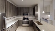 This single-story residence in Fort Mill, SC offers a well-designed layout with contemporary finishes throughout. The kitchen serves as a focal point, showcasing dark wood-toned cabinetry extending to the ceiling, granite countertops, and a full suite of stainless steel appliances including a refrigerator, electric range, and built-in microwave. A peninsula with an undermount sink and pendant lighting above provides both workspace and a natural gathering point, opening directly to the living area. The living room features light hardwood-style flooring, a ceiling fan, and vaulted ceilings that enhance the sense of openness.

A hallway connects the main living spaces to the bedrooms, which are carpeted and receive ample natural light through windows overlooking greenery. Each bedroom includes a ceiling fan for added comfort. Architectural details such as arched built-in shelving and decorative niches add character to the interiors.

The primary bathroom offers a glass-enclosed walk-in shower with tile surround and a granite-topped vanity. A secondary bathroom features a tiled tub-shower combination, granite countertop, and matching dark cabinetry, maintaining a consistent, polished aesthetic throughout the home.