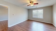 Located at 511 Cobblestone Dr in Wilmington, NC, this single-floor home offers a clean, functional layout with consistent hardwood-style flooring throughout. The open-concept living area connects seamlessly to the kitchen, which serves as a functional centerpiece of the home. The kitchen is outfitted with rich wood cabinetry, granite-style countertops, a full suite of black appliances including a refrigerator, range, microwave, and dishwasher, along with ample counter and storage space. A peninsula-style breakfast bar separates the kitchen from the living area, enhancing the open feel of the shared space. The bedrooms are generously sized, each featuring ceiling fans with light fixtures, textured ceilings, and windows that bring in natural light. The bathroom includes a rich wood vanity with a granite-style countertop, a framed mirror with overhead lighting, a walk-in shower, and hardwood-style flooring that carries throughout. A dedicated in-unit laundry closet with a washer and dryer is conveniently located off the kitchen area. Neutral wall tones, white trim, and consistent finishes give the home a cohesive, move-in-ready aesthetic throughout.