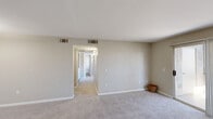 Located in Las Vegas, NV, this single-floor residence offers a practical and comfortable layout with three bedrooms, two bathrooms, a combined kitchen and living area, and a connecting hallway. The living room greets you with neutral-toned carpet, soft taupe walls, and a front entry door with an arched transom window that draws in natural light. It flows seamlessly into the kitchen, which features white cabinetry with crown molding, dark granite-style countertops, stainless steel appliances including a gas range, microwave, and refrigerator, and durable wood-look flooring. The spacious primary bedroom is outfitted with plush carpet, a ceiling fan with light fixture, and a window with vertical blinds. An additional bedroom offers similar carpeted flooring and a bright window, while the living area provides sliding glass door access to an outdoor patio. Both bathrooms are finished with white vanity cabinetry, dark countertops, large mirrors with overhead lighting, and a shower-tub combination, with one bathroom showcasing wood-look tile flooring. A central hallway connects the bedrooms and bathrooms, completing this well-organized and move-in ready home.