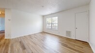 Located at 1475 Wilton Farm Road in Charlottesville, VA, this single-floor, 2-bedroom, 1-bathroom home offers a practical and well-organized layout. The living room is bright and welcoming, featuring light wood-tone flooring, crisp white walls, a textured ceiling, and a large window that lets in natural light and views of the surrounding greenery. An open pass-through connects the living area to the kitchen, which is equipped with dark wood cabinetry, dark granite-style countertops, black appliances including a refrigerator and dishwasher, and a sink — all set over matching light wood flooring. A dedicated dining room provides additional space for daily use. Both bedrooms feature neutral carpet flooring and clean white walls, offering a calm, functional atmosphere. The full bathroom includes wood-look flooring, a white vanity, toilet, and a tub-shower combination. Three closets are distributed throughout the home for ample storage. A dedicated laundry room with wire shelving, washer/dryer hookups, and utility connections adds everyday convenience. A utility room and hallway complete the floor plan. This home provides a straightforward and functional living environment in a residential Charlottesville neighborhood.