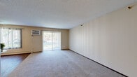 Located at 1351 Hampshire Ave S in St. Louis Park, MN, this 2-bedroom, 1-bathroom residence offers a practical and comfortable single-floor layout. The generously sized living room is a standout feature, with plush carpeting, a textured ceiling, and a wide sliding glass door flanked by vertical blinds that floods the space with natural light and provides outdoor views. A wall-mounted A/C unit and baseboard heating ensure year-round comfort. The kitchen features warm wood-toned cabinetry, hardwood-style flooring, a full-size refrigerator, and a dishwasher, offering efficient functionality. Both bedrooms are carpeted and feature large double bi-fold closets, providing ample storage space. The primary bedroom includes a ceiling fan, a wall-mounted A/C unit, and a window with vertical blinds. The second bedroom also benefits from natural light through a window with vertical blinds. A connecting hallway links the bedrooms to the full bathroom, which includes a shower/tub combination, a vanity with mirror, and clean, neutral finishes. Throughout the residence, a neutral warm-beige color palette creates a cohesive and inviting atmosphere.