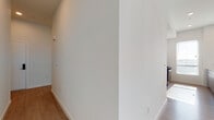 This single-floor residence showcases a clean, contemporary design with light wood flooring and crisp white walls throughout, creating a bright and cohesive aesthetic. The open-concept kitchen and living area serves as the heart of the space, featuring a central island with a granite countertop and built-in sink, stainless steel appliances including a refrigerator, microwave, and range, and two-tone cabinetry in white and dark brown. Large windows fitted with horizontal blinds allow abundant natural light to fill the living area, offering views of the surrounding cityscape. Recessed lighting adds to the well-lit, modern atmosphere. The bedrooms are well-proportioned, each featuring light wood flooring, generous windows, and access to closet space — including a walk-in closet outfitted with wooden hanging rods. The bathrooms are finished with attention to detail: one features a full soaking tub framed by white subway tile, while another includes a granite-topped vanity with white cabinetry, an undermount sink, and a large mirror. Throughout the space, clean lines, neutral tones, and quality materials combine to deliver a functional and contemporary living environment.