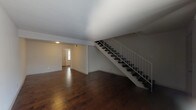 This two-story residence offers a well-organized layout across both levels, finished consistently with rich, dark hardwood flooring that runs throughout the main living areas and bedrooms. The main level features an open living area with a staircase framed by a clean white railing system, leading to the upper floor. Natural light filters in through the front entry door with sidelight, and a vertical blind-covered window brightens the living space further.

The kitchen is outfitted with white cabinetry, granite-look countertops, a stainless steel double-basin sink, a tiled backsplash, and a dishwasher, providing a functional and tidy cooking environment.

A bathroom on the lower level includes a granite-topped vanity with an undermount sink, a framed mirror, and tile flooring. A full bathroom features a soaking tub surrounded by floor-to-ceiling neutral ceramic tile.

The bedrooms are generously sized with hardwood flooring and include closets with double-door or single-door access and built-in rods for storage. One bedroom benefits from a window that admits natural light. Throughout the home, the neutral white walls and clean finishes create a bright, move-in-ready atmosphere that lends itself well to a variety of interior styles.