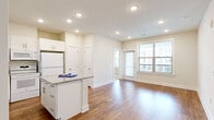 Located at 6820 Communications Pkwy in Plano, TX, this well-designed 2-bedroom, 2-bathroom residence offers a thoughtful single-story layout that maximizes functionality and comfort. The open-concept living and kitchen area serves as the heart of the home, featuring warm wood-style flooring, recessed lighting, and large windows that flood the space with natural light. The kitchen is outfitted with white shaker cabinetry, granite countertops, a center island, a built-in desk or additional counter space along the wall, and white appliances including a refrigerator, range, and microwave. The seamless flow between the kitchen and living room creates an inviting, spacious atmosphere ideal for both everyday living and entertaining. The primary bedroom features wood-style flooring, recessed lighting, a dedicated closet, and a bright window with exterior views. The secondary bedroom is finished with plush carpeting, a ceiling fan, and multiple windows that bring in generous natural light. Both bathrooms are clean and efficiently designed, with one featuring a full tub-shower combination with white tile surround, white cabinetry, and granite-topped vanity. Two closets and a hallway further enhance the practical layout of this Plano residence.