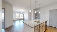 This well-appointed 2-bedroom, 2-bathroom residence in Kansas City, MO offers a thoughtfully designed open-concept floor plan that seamlessly connects the kitchen, dining, and living areas. The kitchen serves as the centerpiece, showcasing a large granite-topped island with an undermount sink, white shaker cabinetry, a blue subway tile backsplash, stainless steel appliances, and elegant pendant lighting. Wood-style flooring flows throughout the main living areas, adding warmth and continuity. The bedrooms are carpeted for comfort, with multiple windows that invite natural light and offer views of the surrounding neighborhood. Three closets, including a spacious walk-in with wire shelving, provide ample storage. The primary bathroom features granite countertops, gray cabinetry, wood-style flooring, and a separate walk-in tiled shower. The secondary bathroom is finished with a soaking tub surrounded by striking marble-look tile. Additional conveniences include a dedicated laundry area and a utility room. With its clean, modern aesthetic, neutral palette, and practical layout, this residence delivers a comfortable and functional living environment.