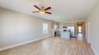Located at 24 Winnow Walk in Wilmington, NC, this single-story home offers a thoughtfully designed open-concept layout with clean, modern finishes throughout. The combined kitchen and living area serves as the heart of the home, featuring light hardwood-style flooring, recessed lighting, and a ceiling fan. The kitchen is well-appointed with gray shaker-style cabinetry, granite countertops, a center island, stainless steel appliances including a refrigerator, range, microwave, and dishwasher, and natural light from dual windows. A bold navy front door with a transom window welcomes you into a bright entryway that flows seamlessly into the main living space. The three bedrooms feature soft carpet flooring and neutral walls, providing a comfortable retreat. The primary bedroom connects to an en-suite bathroom with a single vanity, white countertop, and a glass-enclosed shower, and leads directly to a dedicated walk-in closet. Additional closets provide ample storage throughout. Two laundry areas accommodate washer and dryer units. The attached garage includes an automatic opener and an electrical panel. The home's consistent use of light tones and wood-look flooring creates a cohesive, airy ambiance throughout.