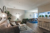Located at 300 Riverside Pkwy in Austell, Georgia, this single-story residence offers a thoughtfully arranged layout designed for comfortable everyday living. The open-concept living and dining area serves as the heart of the home, where wood-look flooring flows throughout and a fireplace with a white mantel anchors the living space. A breakfast bar with counter seating connects the living area to the galley-style kitchen, which is equipped with gray cabinetry, granite-style countertops, a gas range, dishwasher, and full-size refrigerator. The dining area is illuminated by a central pendant light and benefits from natural light streaming through large windows with sheer curtains, creating a bright and welcoming atmosphere. The primary bedroom features plush carpet, a walk-in closet, and ample space for a full furniture arrangement. Additional bedrooms are also carpeted and offer natural light through curtained windows. The bathroom includes gray vanity cabinetry, granite-style countertops, a well-lit vanity mirror, and wood-look flooring. A separate entry area provides a defined transition into the living space, completing this functional and cohesive floor plan.
