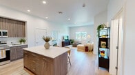 Located at 500 Baker Boulevard in Tukwila, WA, this well-appointed 2-bedroom, 2-bathroom residence offers a thoughtfully designed single-level layout. Light-toned hardwood-style flooring flows throughout, complementing the clean white walls and recessed lighting that give the space a bright, contemporary feel.

The open-concept kitchen and living area serves as the heart of the home. The kitchen features floor-to-ceiling wood-grain cabinetry, stainless steel appliances, and a generous island with a white quartz countertop and bar seating — ideal for both cooking and casual dining. The living area is bathed in natural light from large windows that frame scenic views of the surrounding Tukwila landscape.

Both bedrooms are comfortably sized, with the primary bedroom offering direct access to a private balcony showcasing expansive outdoor views, along with ample closet storage. The second bedroom also enjoys a large window with pleasant views. The two bathrooms are finished with warm wood-tone vanities and light flooring, maintaining a cohesive and clean aesthetic. Additional highlights include four closets for abundant storage and a dedicated in-unit laundry area. This residence combines modern finishes with functional design for comfortable everyday living.