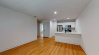 This single-floor unit offers a clean, modern design throughout, highlighted by warm hardwood-style flooring and a bright, neutral color palette that creates a welcoming and cohesive atmosphere. The open-concept layout seamlessly connects the living area to the kitchen, maximizing the sense of space and encouraging easy flow between rooms. Recessed lighting illuminates the living area, which features generous open floor space ideal for a variety of furniture arrangements.

The kitchen is well-appointed with crisp white shaker-style cabinetry extending to the ceiling for ample storage, a subway tile backsplash, and a full suite of stainless steel appliances including a refrigerator, range, and microwave. A peninsula with a white countertop and a matte black faucet and undermount sink serves as both a functional workspace and a casual dining or gathering spot.

The bedrooms continue the hardwood-style flooring and are bathed in natural light through windows fitted with blinds. Ceiling fans provide additional comfort. The bathroom is a standout feature, showcasing striking large-format marble-look tile flooring with dramatic veining, paired with matte black fixtures, a white vanity with clean countertops, and a full tub-shower combination with white tile surround — delivering a polished, contemporary finish throughout.