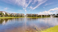 This single-floor residence is part of a well-appointed Mediterranean-inspired community that immediately impresses with its striking outdoor setting. The exterior showcases warm terracotta rooflines, stucco facades, and lush landscaping that frames a serene community lake. A central fountain rises gracefully from the water, creating a tranquil focal point visible from the grounds, while tall palm trees and manicured lawns reinforce the resort-like atmosphere. The community's multi-building layout is designed to maximize waterfront views and outdoor enjoyment, offering residents a picturesque backdrop that reflects the relaxed elegance of Florida living. The interior details of this particular unit are not fully captured in the available imagery; however, as part of this thoughtfully designed community, the residence is expected to reflect the same quality and attention to detail seen throughout the property. The overall ambiance of the community is one of calm sophistication, blending natural surroundings with architectural character to create a welcoming and visually appealing living environment. The combination of the waterfront setting, lush tropical landscaping, and cohesive architectural design make this a distinctive and desirable place to call home.