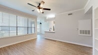 Located at 200 Kellington Dr N in Houston, TX, this single-story, 3-bedroom, 2-bathroom home offers a well-designed layout with consistent light wood-style flooring throughout. The open-concept living and kitchen area anchors the home, featuring crown molding, a ceiling fan with light fixture, and large windows with horizontal blinds that invite abundant natural light. The kitchen includes a peninsula with a white quartz countertop, a black matte faucet with undermount sink, white cabinetry, stainless steel appliances, recessed lighting, and a built-in shelving unit nearby. An in-unit washer and water heater are conveniently tucked behind a utility closet. The primary bedroom is generously sized, boasting a ceiling fan, natural light from a window overlooking greenery, and access to a private en-suite bathroom with a dual-sink white vanity, black hardware accents, a large mirror, and a tub-shower combo. A second standout bedroom features a striking arched window that frames outdoor tree views. The additional bedrooms and bathrooms maintain the same clean, neutral aesthetic. A walk-in closet with wire shelving provides ample storage. The home's cohesive design palette of white walls and warm wood floors creates a bright, modern, and move-in-ready atmosphere throughout.