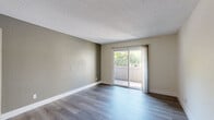 Located at 7236 Greenhaven Dr in Sacramento, CA, this well-designed one-bedroom, one-bathroom residence offers a thoughtful layout across a single floor. The open-concept living room and kitchen area is anchored by smooth hardwood-style flooring and a textured ceiling, with a sliding glass door that opens to a private balcony overlooking lush greenery — filling the space with natural light and outdoor views. The kitchen is a standout feature, showcasing sleek gray shaker-style cabinetry, white countertops, a subway tile backsplash, and a full suite of stainless steel appliances including a range, refrigerator, and dishwasher. A ceiling fan with lighting adds both function and style to the combined living and kitchen area. The bedroom offers plush carpeting, neutral-toned walls, and a closet for convenient storage. The bathroom is cleanly finished with gray vanity cabinetry, a white countertop, a single-basin sink, and a tub-shower combination enclosed by sliding glass doors. Light wood-style flooring ties the bathroom together with a bright, clean aesthetic. A hallway connects the rooms efficiently, completing this compact yet functional home.