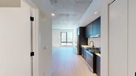Located at 625 North 2nd Avenue in downtown Phoenix, AZ, this modern studio offers a thoughtfully designed single-floor layout that maximizes every square foot. The open-plan living, dining, and kitchen area forms the heart of the space, anchored by light-toned hardwood flooring and striking exposed concrete ceilings that lend an industrial-chic aesthetic. A large picture window frames views of the Phoenix skyline, flooding the living area with natural light and creating a sense of openness well beyond the unit's footprint. The kitchen is outfitted with dark, flat-front cabinetry extending to the ceiling, a white tile backsplash, light quartz countertops, and a full suite of stainless steel appliances including a gas range, dishwasher, and French door refrigerator — all complemented by matte black fixtures for a cohesive, contemporary look. The bathroom features large-format tile flooring, a floating wood vanity with an undermount sink, an illuminated mirror, and matte black hardware accents. A dedicated closet and in-unit laundry add practical convenience. Recessed lighting throughout ensures a well-lit, polished environment, while the clean white walls provide a neutral backdrop that enhances the modern, urban character of the space.