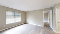 Located at 3780 University Club Blvd in Jacksonville, FL, this 2-bedroom, 1-bathroom unit is designed with a clean, neutral aesthetic throughout. Light wood-style flooring flows consistently across the entire floor plan, complementing the warm greige wall tones and crisp white trim found in every room. The kitchen is a standout feature, showcasing white shaker-style cabinetry, a striking marble-look quartz countertop with a peninsula, a deep sink, and black appliances including a refrigerator, dishwasher, and range. Louvered closet doors near the kitchen provide additional storage. The open living area connects seamlessly to the rest of the unit, with natural light filtering in through window blinds. Both bedrooms are generously proportioned, each featuring windows with blinds and textured ceilings. The spacious primary bedroom benefits from a large walk-in closet outfitted with wire shelving and hanging rods. The bathroom includes a full tub-shower combination with white tile surround, a vanity, and wood-style flooring. Throughout the unit, textured ceilings and consistent finishes create a cohesive, well-maintained living environment.