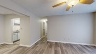 This single-story unit offers a practical and well-organized layout across two bedrooms and two bathrooms. The main living and dining area features wood-look plank flooring and neutral gray walls, with a ceiling fan providing comfort overhead. A textured ceiling adds subtle character throughout the common areas. The space connects through a central hallway leading to the private rooms.

The galley-style kitchen is equipped with gray cabinetry, light countertops, a stainless sink, a dishwasher, and black appliances including a refrigerator and range. Wood-look flooring continues throughout the kitchen, maintaining a cohesive aesthetic.

Both bedrooms feature plush carpet flooring and neutral tones. The primary bedroom is a well-sized room with a window allowing natural light. The second bedroom also offers carpeted floors and a closet. Both bathrooms are straightforward in design, with one featuring a tub-shower combination with built-in shelving and chrome fixtures, and the other offering a vanity with a mirrored medicine cabinet and chrome hardware.

A dedicated laundry room with wire shelving overhead and washer/dryer hookups rounds out this efficiently arranged unit.
