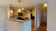 Located at 12251 Elm Forest Ct in Clarksburg, MD, this two-floor unit offers a thoughtfully designed layout across multiple levels connected by a staircase. The living room is a standout space, featuring dramatic vaulted ceilings that lend an open, airy feel, a corner fireplace with a clean white mantle, and a large sliding glass door that fills the room with natural light and provides views of the surrounding greenery. The kitchen is well-appointed with warm honey-toned cabinetry, dark granite-style countertops, black appliances including a gas range, microwave, refrigerator, and dishwasher, along with a sink, track lighting, and pendant light accents. Hardwood-style flooring runs throughout the kitchen and dining areas. The bedrooms are carpeted and bathed in natural light through large windows fitted with blinds, offering views of the neighborhood and surrounding trees. Each bedroom includes a closet for storage. The bathrooms feature hardwood-style flooring, wood-toned vanity cabinetry, and clean white fixtures. One bathroom includes a shower stall, while the other provides a full tub-shower combination. The upper level offers an open loft-style overlook, adding visual depth and an open-concept feel to the overall floor plan.