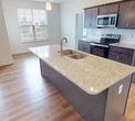 This 990 square foot apartment offers a blend of contemporary design and practical living spaces. The open-concept living area is anchored by a modern kitchen, featuring dark wood cabinetry, stainless steel appliances, and a spacious island with a quartz countertop. The kitchen's subway tile backsplash and pendant lighting add stylish touches.

Hardwood floors extend throughout the main living areas, while large windows flood the space with natural light, offering views of the surrounding area. The primary bedroom, measuring 180 square feet, and the second bedroom both feature plush carpeting for added comfort.

Both bathrooms are finished with clean, white fixtures and tiling, providing a bright and hygienic atmosphere. One bathroom includes a shower stall, while the other offers a full-size bathtub.

The unit includes an in-unit laundry area with full-size washer and dryer, adding convenience to daily life. The apartment's neutral color palette and modern finishes create a versatile canvas for various decorating styles.

Located on the third floor of the Legacy building in Etters, PA, this apartment combines contemporary living with the charm of a smaller town setting.