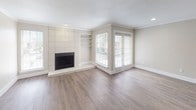 This single-floor residence offers a clean, modern aesthetic with an open-concept design that connects the main living areas seamlessly. The living room is a standout space, anchored by a tile-surround fireplace flanked by built-in shelving, all set against warm hardwood-style flooring. Large windows and a sliding glass door flood the room with natural light while providing views of the outdoors, creating an airy and inviting atmosphere. Crown molding and a textured ceiling add classic finishing touches throughout.

The kitchen is efficiently designed with gray shaker-style cabinetry, white quartz countertops, and a classic white subway tile backsplash. Stainless steel appliances — including a refrigerator, over-the-range microwave, and range — provide a polished, functional workspace. A peninsula counter extends into the open living and dining area, making it ideal for casual dining or entertaining.

Two bathrooms echo the home's contemporary palette. Both feature gray vanity cabinetry, white quartz countertops, and framed mirrors with bright vanity lighting. One bathroom includes a tub-shower combination, while the other offers an extended vanity countertop with additional storage. Soft, neutral tones throughout the space create a cohesive and welcoming environment from room to room.
