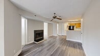 Located at 201 Kingstowne Rd in Newport News, VA, this two-bedroom, one-bathroom residence offers a well-organized single-floor layout designed for comfortable everyday living. The open-concept living and kitchen area serves as the heart of the home, featuring durable hardwood-style flooring, a ceiling fan, and a classic wood-burning fireplace that anchors the living space. The kitchen is equipped with warm honey-toned cabinetry, black appliances including a range and refrigerator, a peninsula with a breakfast bar, and a stainless steel sink — providing ample functionality and storage. The primary bedroom features its own ceiling fan and multiple closets, while the second bedroom is carpeted and benefits from vaulted ceilings and an arched window that invites natural light. A third bedroom area includes sliding mirrored closet doors and additional window views. Four closets are distributed throughout the unit, offering generous storage solutions. Sliding glass doors in one of the bedrooms open to a private balcony, extending the living space outdoors. The unit also includes a dedicated laundry area for added convenience. Neutral tones and clean finishes throughout give the space a bright, move-in-ready ambiance.