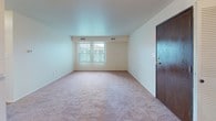 This single-floor residence is thoughtfully laid out, offering a comfortable and functional living environment across several well-defined spaces. The open living and dining area serves as the heart of the home, featuring neutral-toned carpet, white walls, and a chandelier overhead that adds a classic touch. Natural light filters in through windows, creating a bright and welcoming atmosphere. A pass-through counter connects the living space to the kitchen, enhancing the open feel.

The galley-style kitchen is efficiently designed with warm wood cabinetry lining both sides, light countertops, a stainless steel sink, and white appliances including a refrigerator, stove, and dishwasher. The tile flooring adds practicality to this well-equipped cooking space.

The bedrooms are carpeted and generously proportioned, each benefiting from natural light and notable storage. One bedroom features dual closets with louvered bifold doors, providing abundant wardrobe space, while another includes a walk-in closet with built-in shelving.

The full bathroom includes a single-sink vanity with wood cabinetry, a medicine cabinet with mirror, tile flooring, and a bathtub with tiled surround. A utility area with HVAC equipment is also accessible, adding to the home's practical amenities.