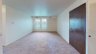 This single-floor residence is thoughtfully laid out, offering a comfortable and functional living environment across several well-defined spaces. The open living and dining area serves as the heart of the home, featuring neutral-toned carpet, white walls, and a chandelier overhead that adds a classic touch. Natural light filters in through windows, creating a bright and welcoming atmosphere. A pass-through counter connects the living space to the kitchen, enhancing the open feel.

The galley-style kitchen is efficiently designed with warm wood cabinetry lining both sides, light countertops, a stainless steel sink, and white appliances including a refrigerator, stove, and dishwasher. The tile flooring adds practicality to this well-equipped cooking space.

The bedrooms are carpeted and generously proportioned, each benefiting from natural light and notable storage. One bedroom features dual closets with louvered bifold doors, providing abundant wardrobe space, while another includes a walk-in closet with built-in shelving.

The full bathroom includes a single-sink vanity with wood cabinetry, a medicine cabinet with mirror, tile flooring, and a bathtub with tiled surround. A utility area with HVAC equipment is also accessible, adding to the home's practical amenities.