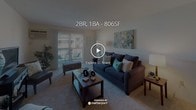 This single-floor, two-bedroom, one-bathroom residence offers a thoughtfully arranged layout with comfortable living spaces throughout. The living room is carpeted and features a sliding glass door that opens to a private balcony, allowing natural light to fill the room and providing outdoor views of the surrounding area. A wall-mounted air conditioning unit and baseboard heating are also present in the living space.

The kitchen is well-equipped with warm-toned wood cabinetry, dark countertops, tile flooring, and white appliances including a gas range, dishwasher, and refrigerator. A sink with a small window above it adds a practical touch to this functional cooking space.

The primary bedroom is generously sized, featuring plush carpeting, a large closet with paneled doors, and a sliding glass door leading directly to the balcony. The second bedroom also offers carpeted flooring, a built-in closet, and large windows that bring in ample natural light, making it suitable as a bedroom or home office.

The bathroom includes a tub-shower combination with blue tile surround, tile flooring, and a wood-toned vanity with a white countertop, completing this comfortable and practical residence.