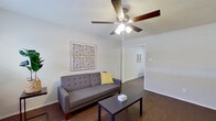 This single-floor, 2-bedroom, 1-bathroom home offers a well-organized layout designed for comfortable everyday living. The living room serves as the central gathering space, featuring dark hardwood-style flooring, a ceiling fan with integrated lighting, and a textured ceiling. Natural light filters in through a window, creating a bright and welcoming atmosphere.

The kitchen is efficiently designed with white cabinetry, a double-basin stainless steel sink, white appliances including a refrigerator and dishwasher, and ample upper and lower cabinet storage for all culinary needs.

The primary bedroom is generously sized, offering room for a full furniture arrangement, a ceiling fan, a window with blinds, and two closets — providing notable storage capacity. The second bedroom mirrors the same hardwood-style flooring and ceiling fan, with a window that brings in natural light.

The shared full bathroom includes a white vanity with storage, a toilet, overhead cabinetry, and a tub-shower combination with tile surround and a curtain enclosure.

A dedicated laundry area is equipped with washer and dryer hookups and overhead white cabinetry for additional storage. Consistent dark wood-style flooring and neutral walls throughout give the home a cohesive, clean aesthetic.