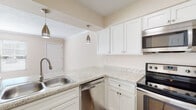 Located at 555 Jeanette Benton Dr in Evansville, Indiana, this single-floor residence offers a clean, functional layout with contemporary finishes throughout. The kitchen is a standout feature, showcasing crisp white shaker cabinetry, light granite-style countertops, and a full suite of stainless steel appliances including an electric range, built-in microwave, dishwasher, and refrigerator. Stylish pendant lighting hangs above the kitchen peninsula, which opens to the adjacent living area, creating a connected and practical flow. The living spaces are bright and welcoming, featuring warm hardwood-style flooring, neutral beige tones, and crown molding that adds a refined touch. Windows with blinds allow natural light to pour in throughout. The bedrooms are comfortably sized, each equipped with ceiling fans and ample natural light. One bedroom benefits from direct access to a bathroom and features a generously proportioned walk-in closet with wire shelving on multiple walls, offering excellent storage capacity. The bathroom includes a full tub-shower combination with chrome fixtures in a clean, all-white surround. Textured ceilings and consistent trim work are present throughout, contributing to the cohesive and tidy character of this single-level home.