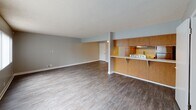 Located at 1718 Ximeno Ave in Long Beach, California, this single-floor unit offers a functional and well-maintained layout designed for comfortable everyday living. The open-concept living and dining area is spacious and filled with natural light streaming through multiple large windows dressed with vertical blinds. Durable hardwood-style flooring runs throughout the space, complementing the neutral gray walls and clean white baseboards. A textured ceiling adds a classic touch to the main living area, which also features a wall-mounted AC unit for year-round comfort. The kitchen is positioned along a pass-through counter with warm wood cabinetry, a stainless steel refrigerator, a stainless steel sink with white countertops, and dedicated appliance space. The layout connects seamlessly to the living area, making it ideal for everyday use. The bedrooms are well-sized with the same hardwood-style flooring and soft neutral tones. One bedroom features mirrored sliding closet doors, enhancing the sense of space. The full bathroom is clean and bright, outfitted with a wall-mounted wood vanity, a large mirror, a tub-shower combination, and elegant globe lighting. The overall ambiance of the unit is clean, modern, and move-in ready.