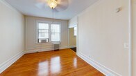 Located in Washington, DC's Cathedral Heights neighborhood, Apartment 204 at 3621 Newark St NW is a well-maintained residence that blends classic architectural details with functional design. The unit is accessed through a foyer entry with warm hardwood flooring and clean white walls that carry throughout the living spaces.

The main living area is generously proportioned, showcasing rich, polished hardwood floors, crisp crown molding, and classic panel detailing on the walls. Multiple windows fitted with blinds allow ample natural light to fill the room, while a ceiling fan with a light fixture provides year-round comfort. Cast iron radiators offer efficient, traditional heating.

An open passage connects the living area to additional rooms, maintaining a sense of flow throughout the unit. The kitchen features rich, dark cherry wood cabinetry, dark granite countertops, a stainless steel gas range, and dark hardwood floors — offering a stylish and functional cooking space with ample storage.

The bathroom is finished with tile flooring, a combination shower and soaking tub, a vanity with an integrated sink, and a window for natural ventilation and light. Throughout the apartment, the consistent use of hardwood floors, detailed moldings, and neutral tones creates a cohesive, classic aesthetic well-suited to comfortable urban living.