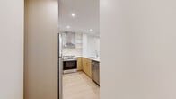 Located at 2826 Jacklin Rd in Victoria, BC, this contemporary two-bedroom, one-bathroom residence offers a thoughtfully designed open-concept layout with modern finishes throughout. Light oak-toned flooring runs continuously across the space, lending warmth and cohesion to every room.

The heart of the home is a well-appointed kitchen that seamlessly flows into the dining and living areas. It features a large central island with a striking marble-look quartz countertop and undermount sink, complemented by matching backsplash. Warm wood lower cabinetry pairs with crisp white upper cabinets, while stainless steel appliances complete the polished look.

The two bedrooms are bright and airy, each benefiting from natural light through large windows that frame picturesque views of the surrounding trees and skyline. Exposed concrete columns add an industrial accent to the clean, minimalist aesthetic. Baseboard heating ensures year-round comfort.

The bathroom is finished to a high standard, showcasing marble-look tile in the walk-in shower, a sleek wood-toned vanity with a white quartz countertop, and a full mirror. Three closets provide ample storage throughout the unit. Additional conveniences include in-unit laundry and a private balcony, making this a well-rounded and functional residence.